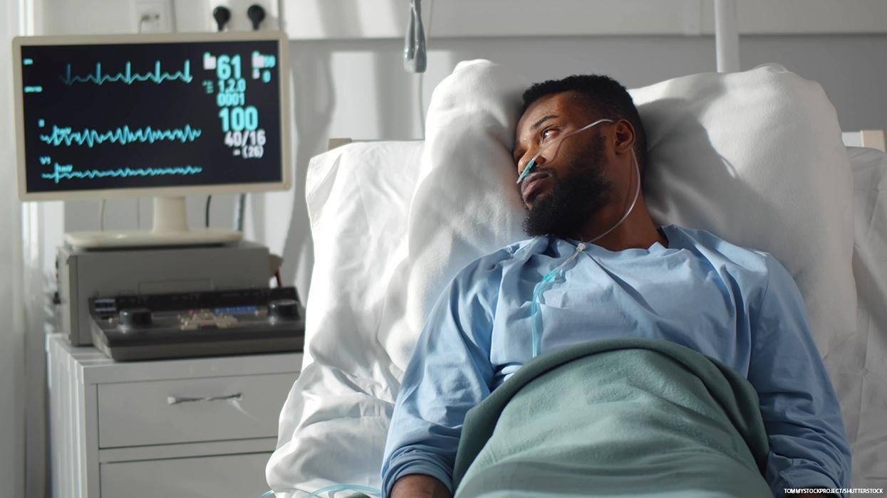 A Black man recovers in a hospital bed.