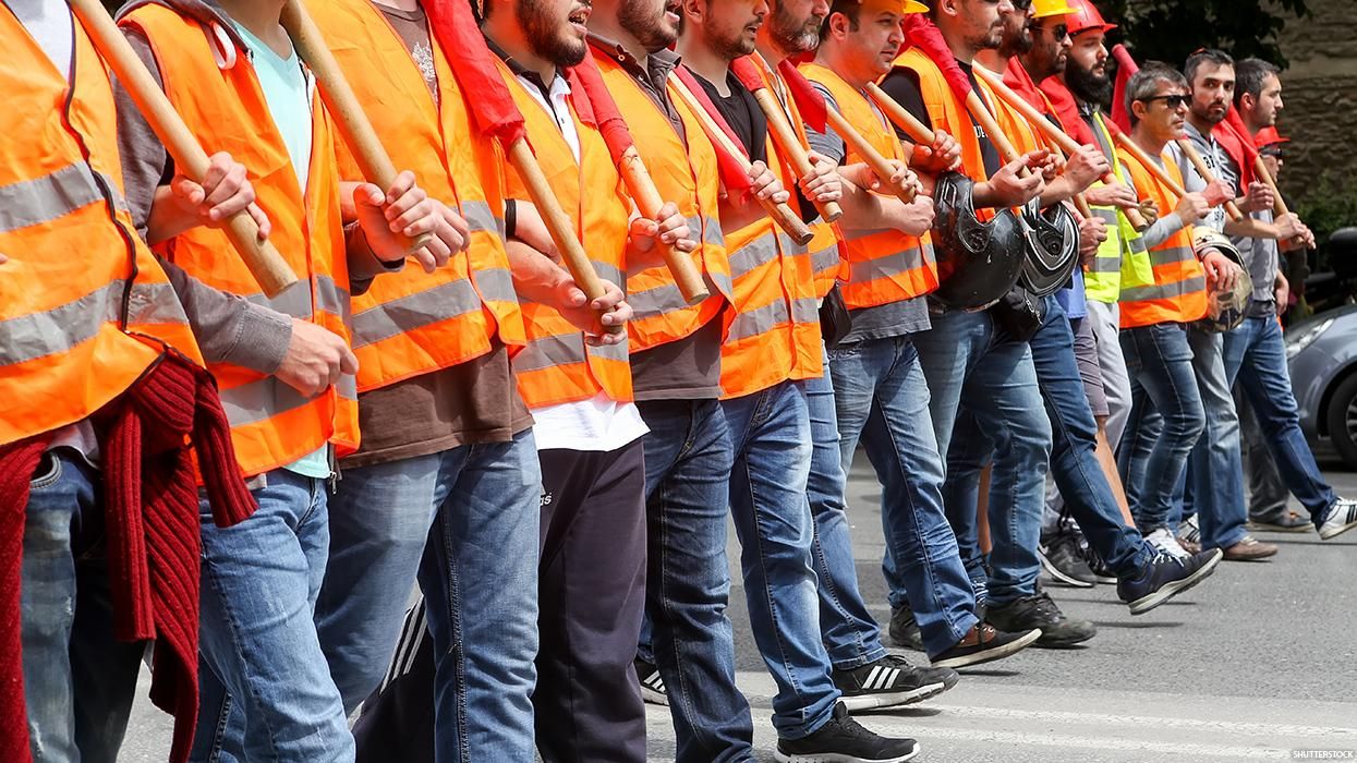 A line of striking workers in orange vests holding hands
