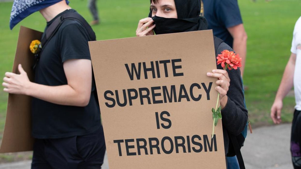 A protestor holds a sign that reads: "White supremacy is terrorism"