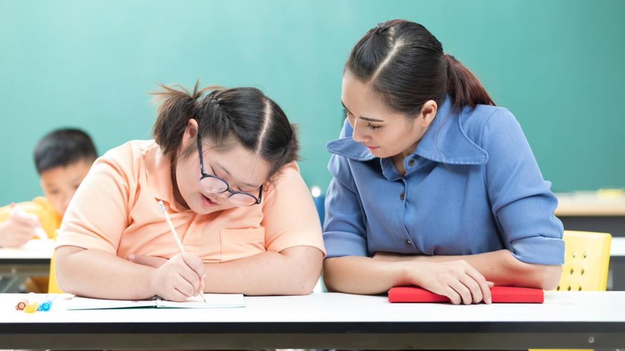 A teacher assists a student with Down Syndrome 