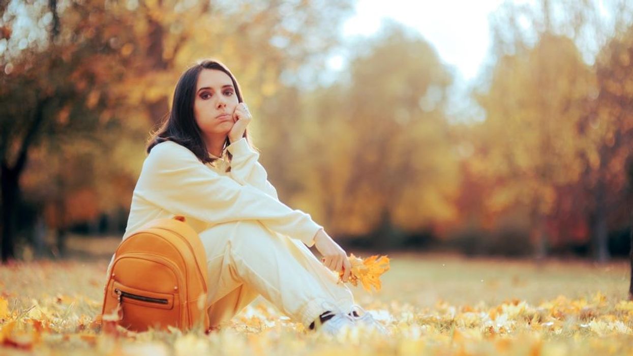 A woman sits in a field of leaves