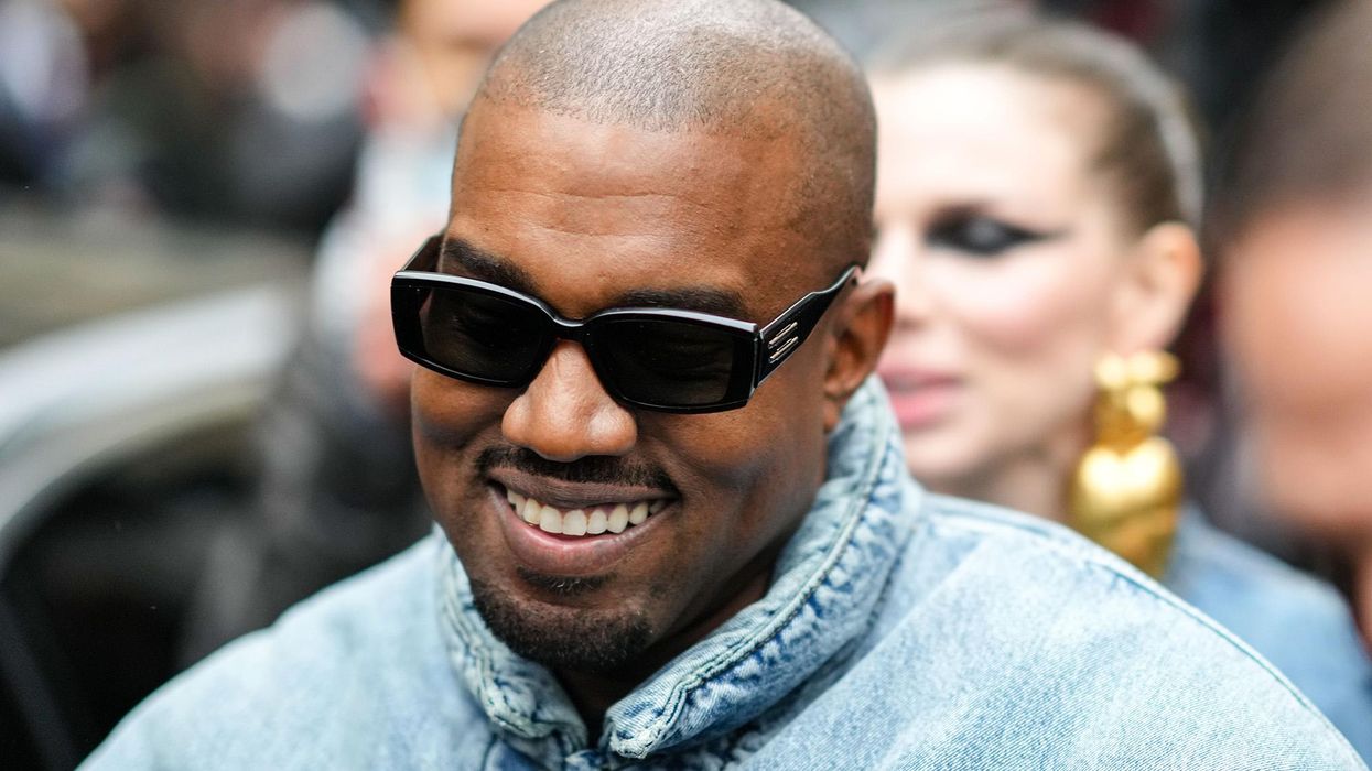 Kanye West smiles with sunglasses on