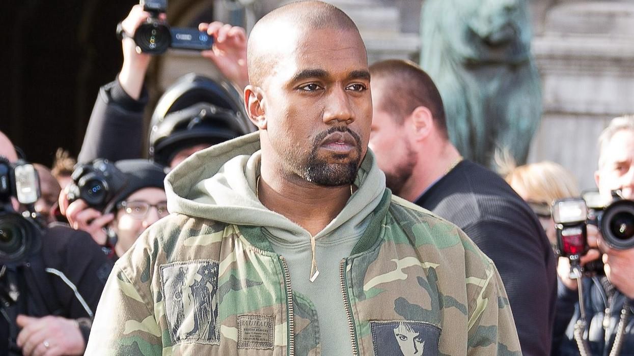 Kanye West walks through a crowd of paparazzi.