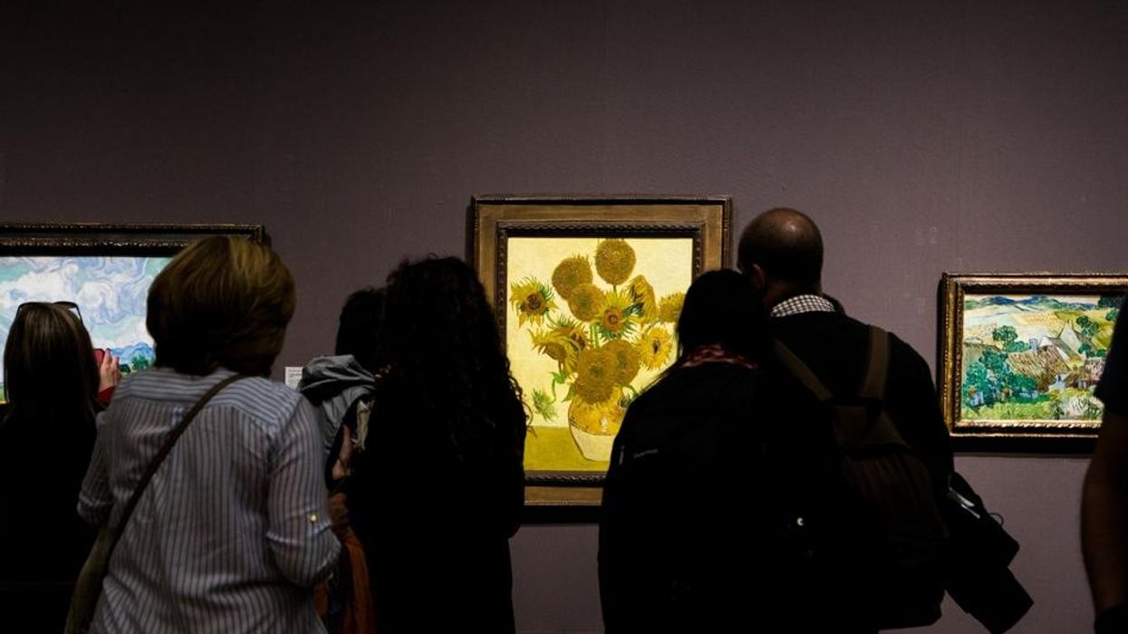 Museum goers observe Sunflowers by Van Gogh