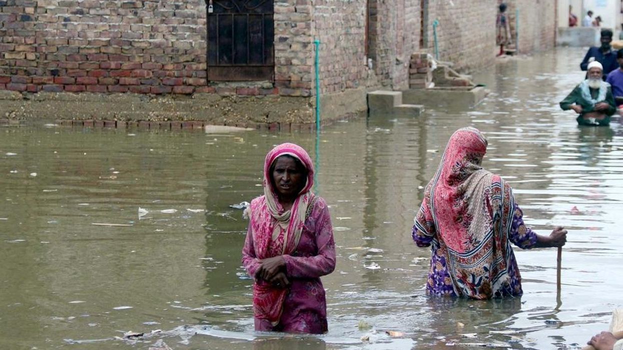 Two women wade through water from severe flooding in Pakistan